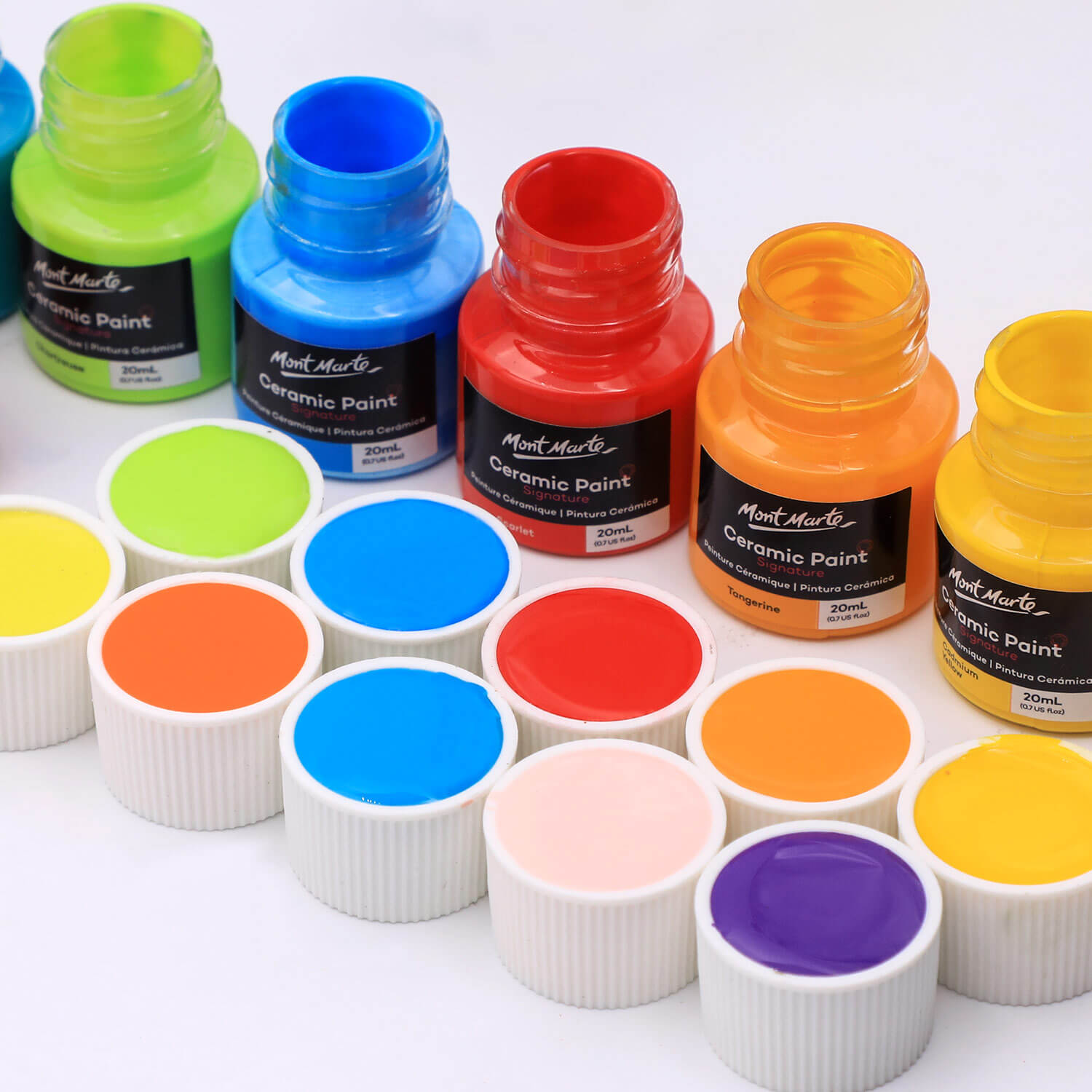 A line of Mont Marte ceramic paints all brightly coloured with lids full of paint.