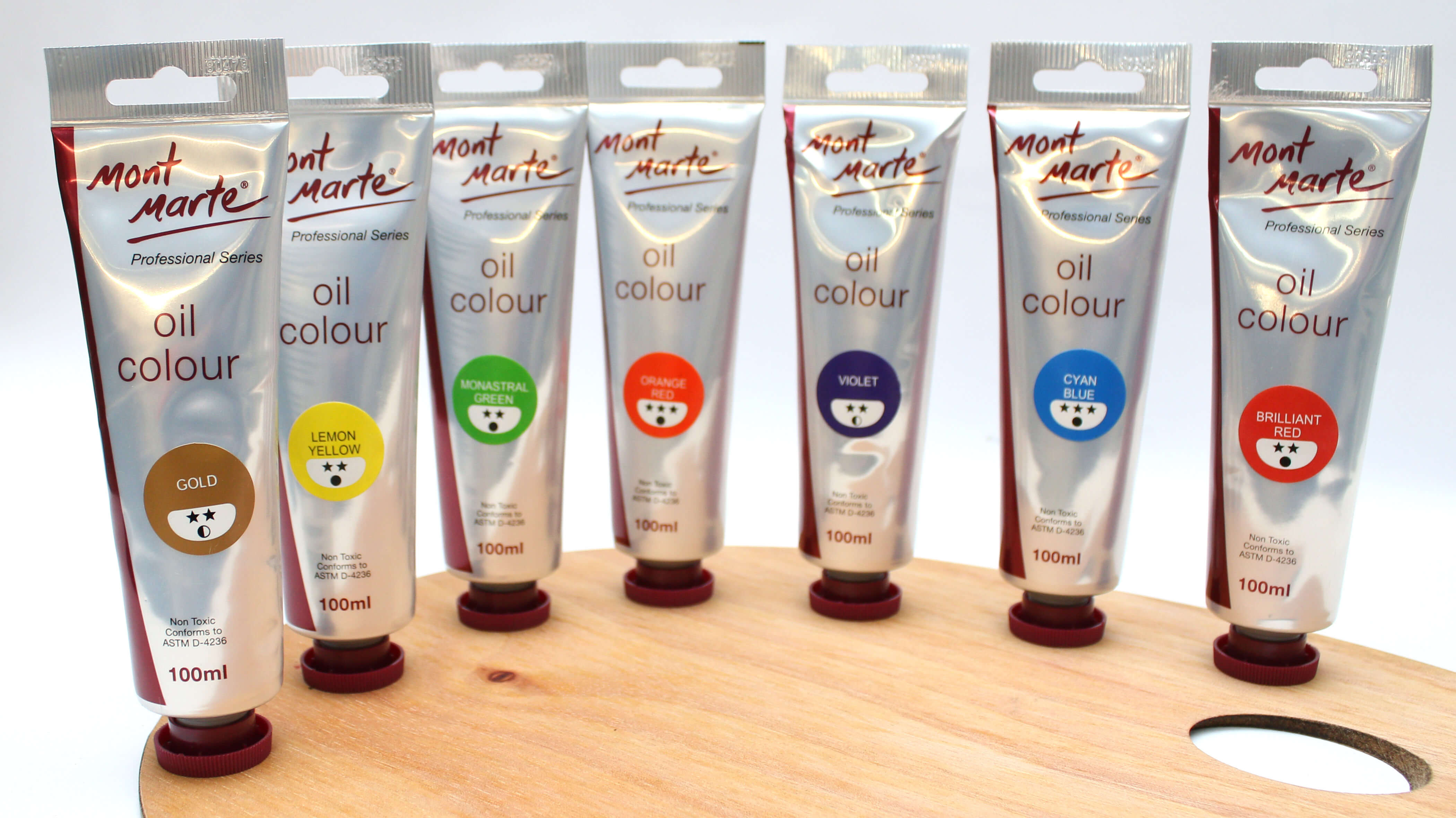 A range of Mont Marte oil paints standing upright on a wooden palette.