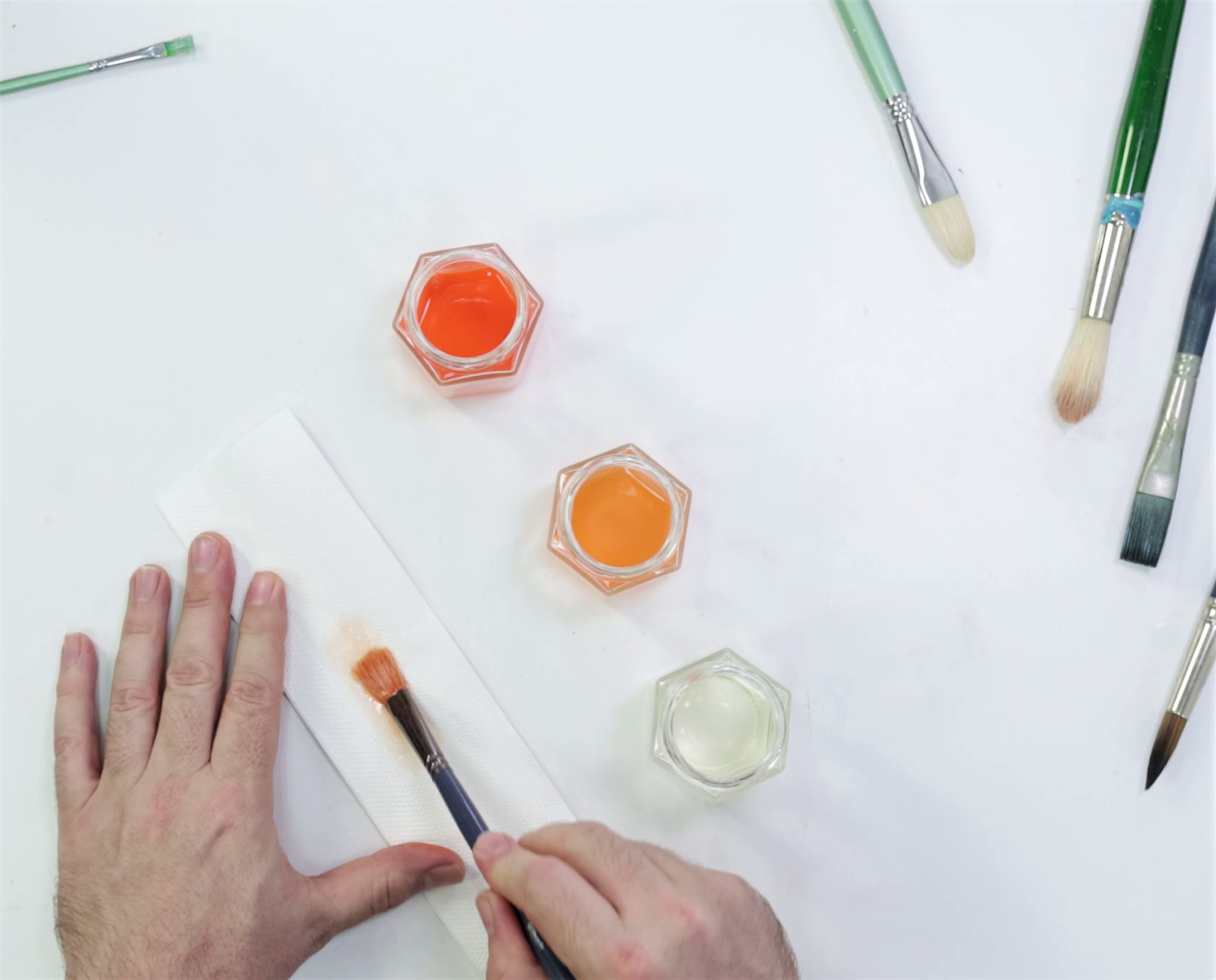 5. Oil brush being cleaned with three small containers of solvent