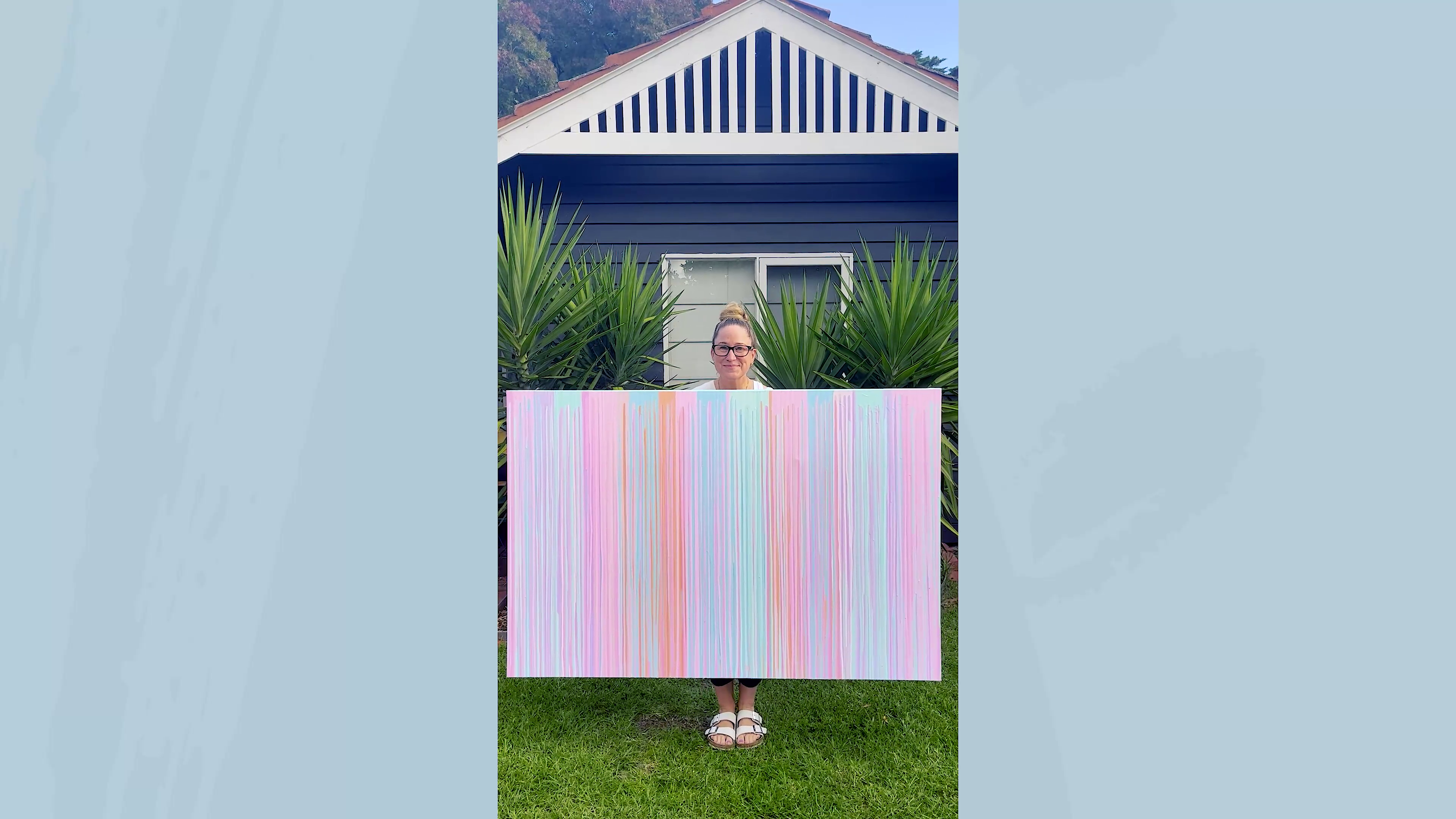 5. Poppy Key holding her pastel drip painting while standing on grass