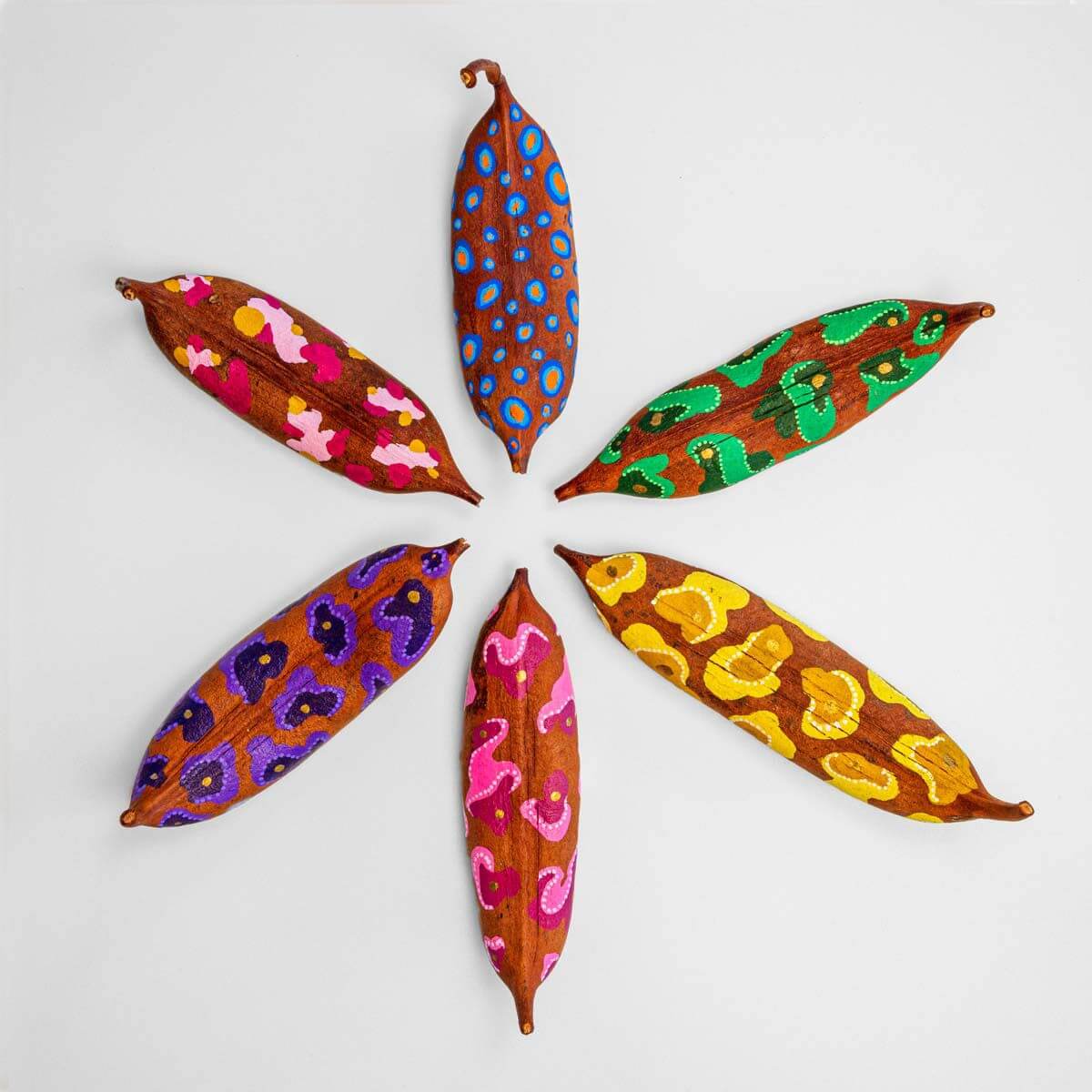 5. Six painted leaves in various bright colours and patterns laid out onto a white table.