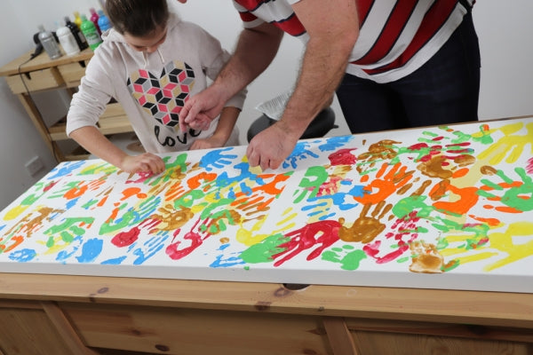 A man and a child creating a hand painting.