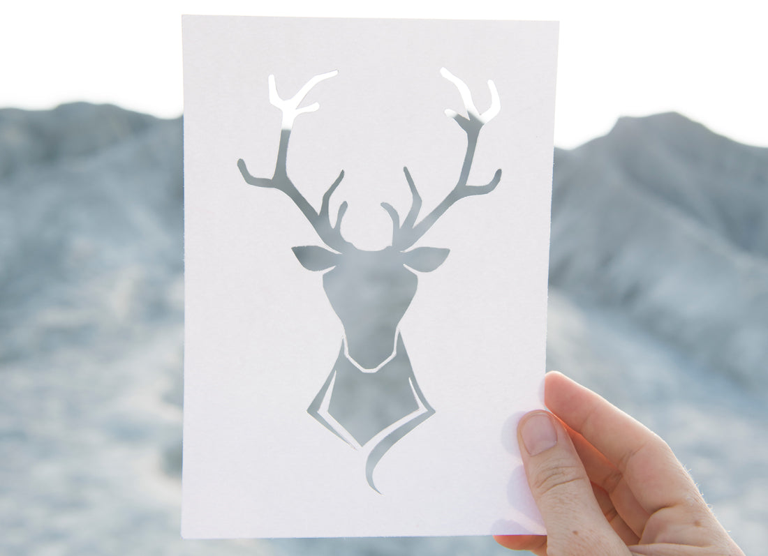 Hand holding a reindeer paper cut out.