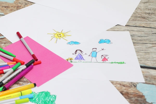 Coloured markers and pieces of copy paper with a child's family drawing. 