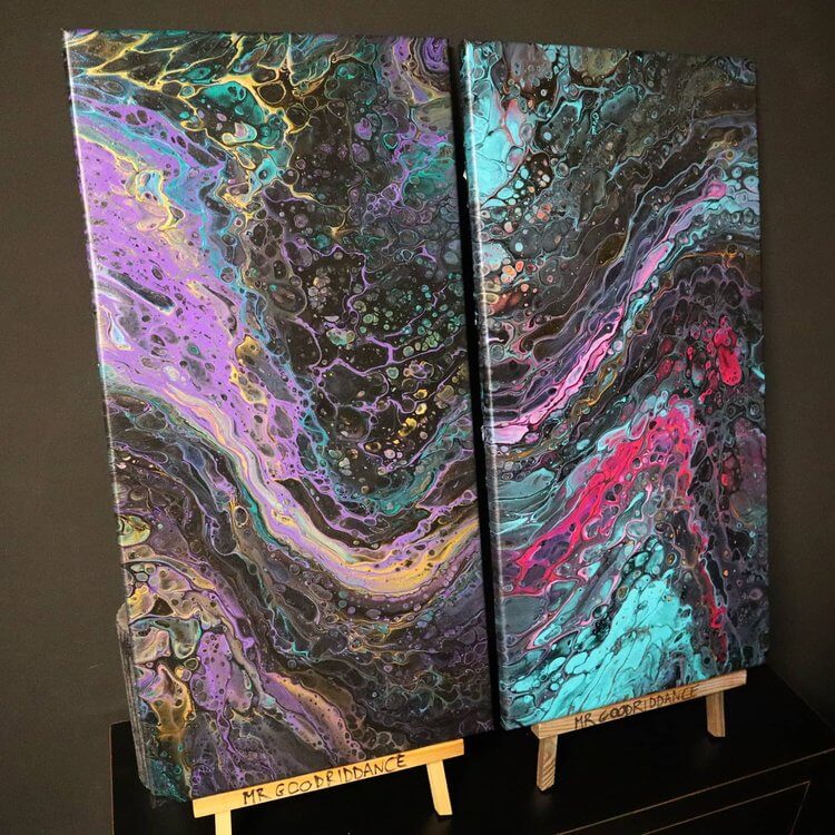 A black, blue pink and purple pour painting on two wooden easels.