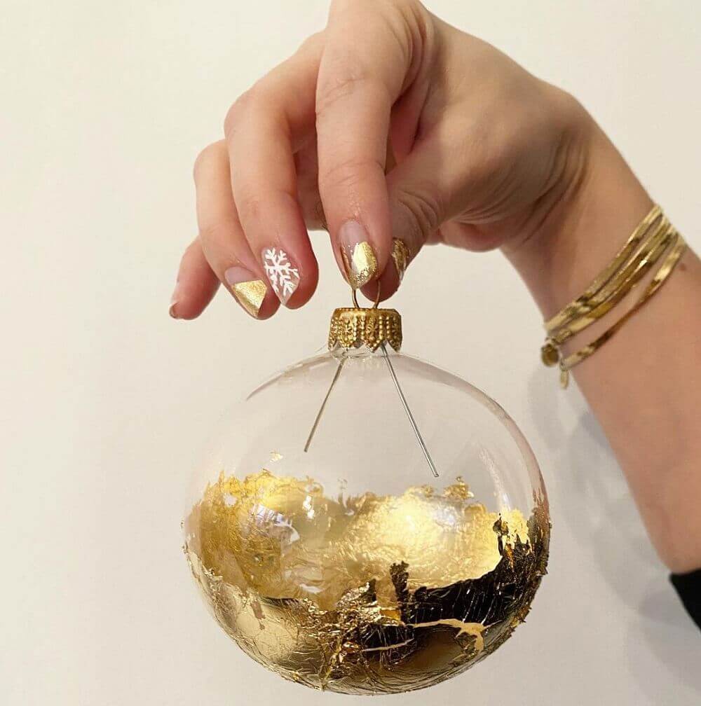 Hand holding a Christmas bauble dripped in gold leaf.