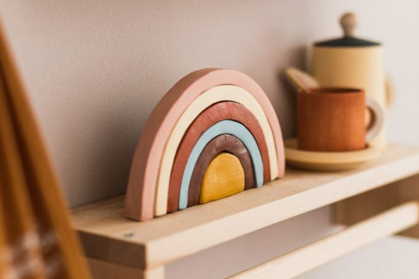 A rainbow air dry clay décor piece on a mantlepiece.