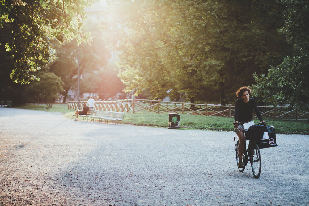 People riding bikes and walking in a park on a sunny afternoon.