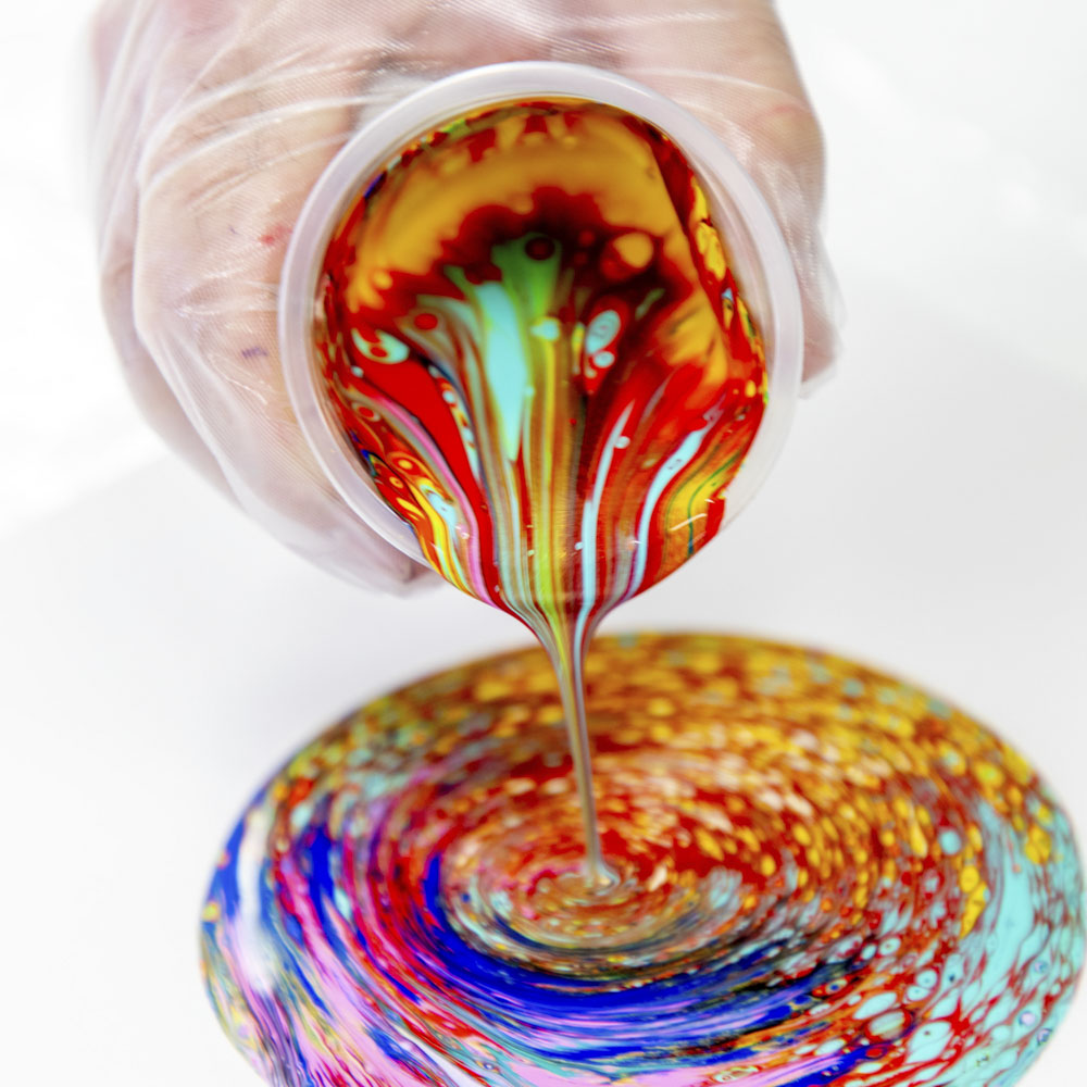 6. Acrylic Flow Medium mixed with many vibrant shades of acrylic paint being poured from a plastic cup