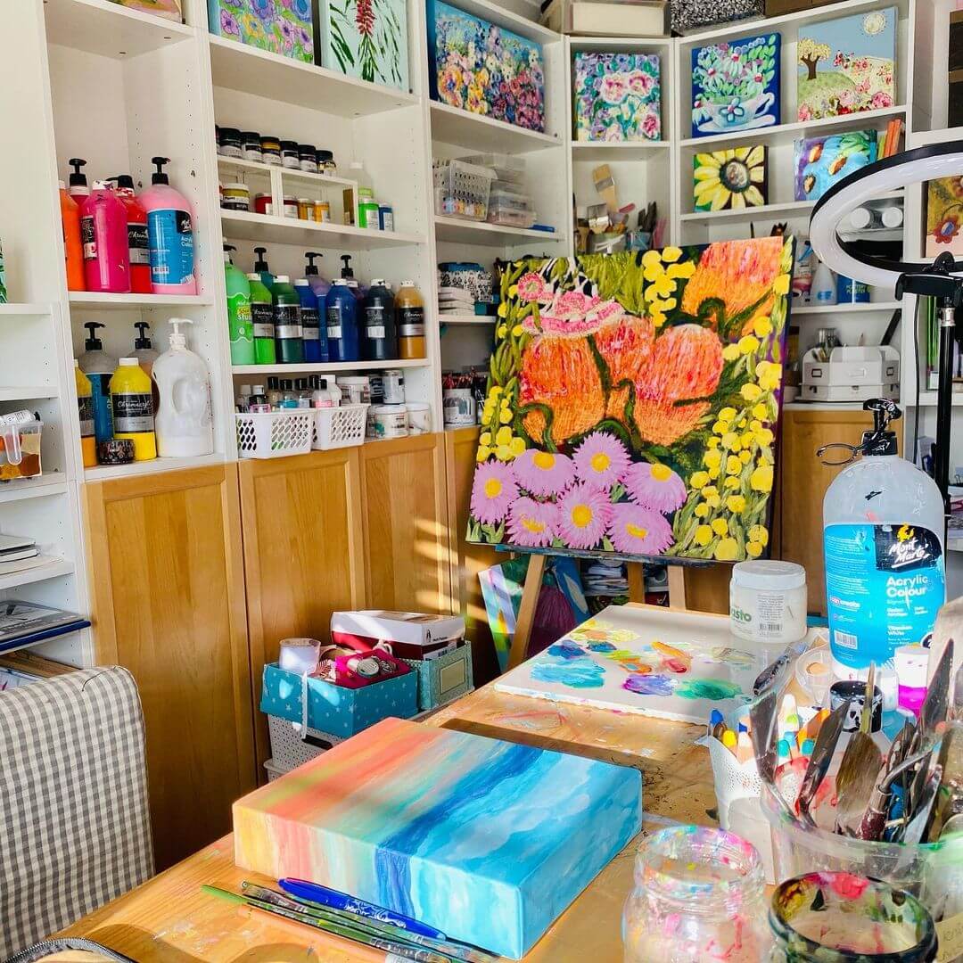 An artwork of spring flowers on an easel in a bright studio with various Mont Marte paint products around.