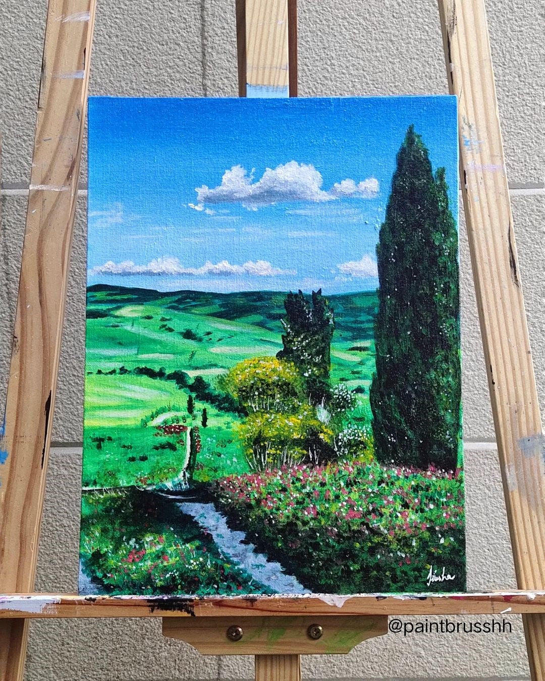 An easel with a vibrant rural landscape on the canvas.
