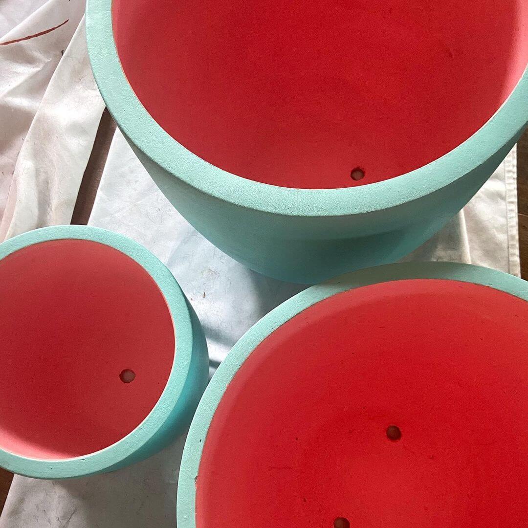 Blue terracotta pots painted with a watermelon pink inside of the pot also painted.
