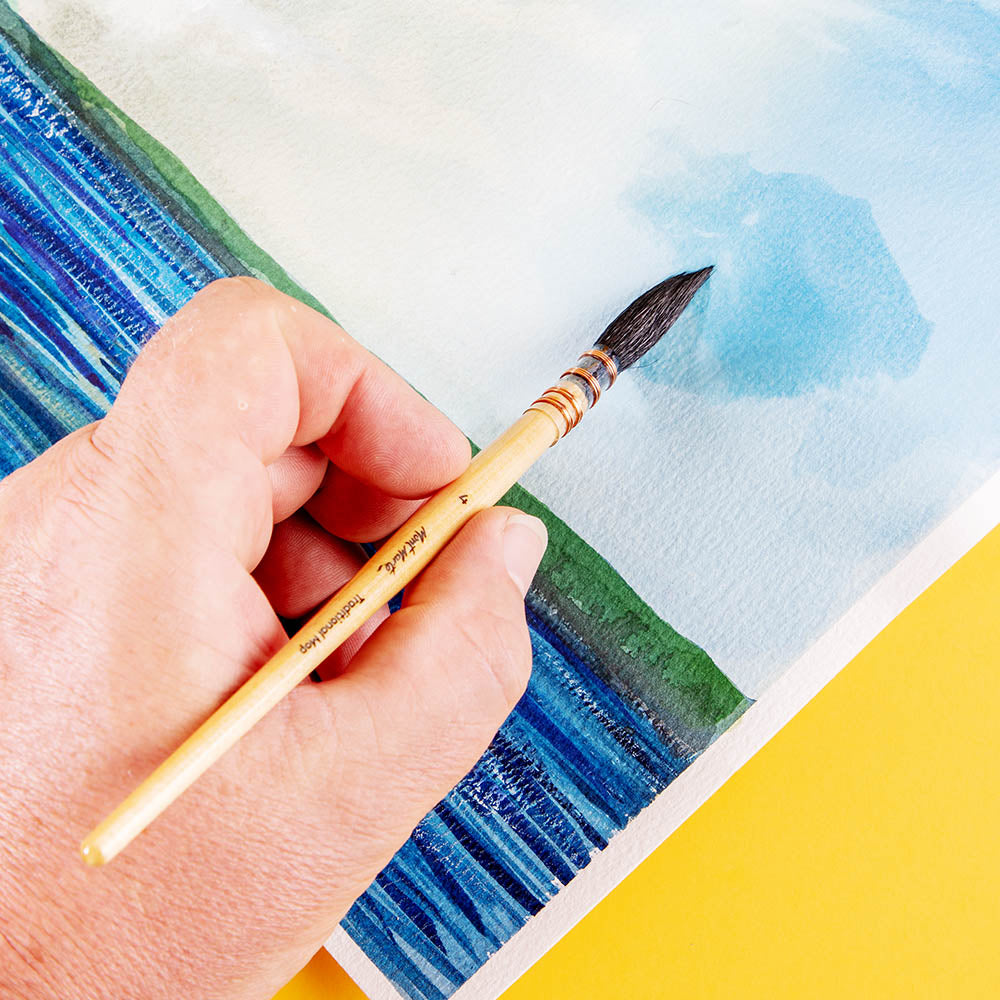 6. Diluted blue watercolour being painted to a blue sky on paper