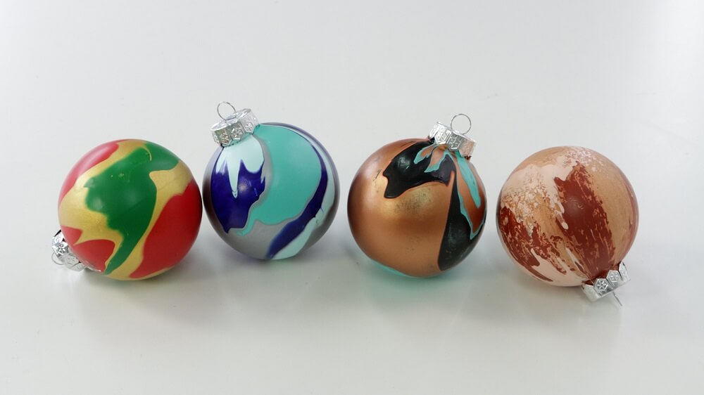 Four baubles painted with pouring paint.