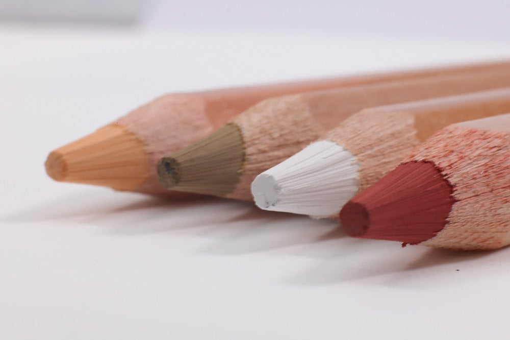 Four coloured pastel pencils lying on a white background with a close up of the pencil's leads.