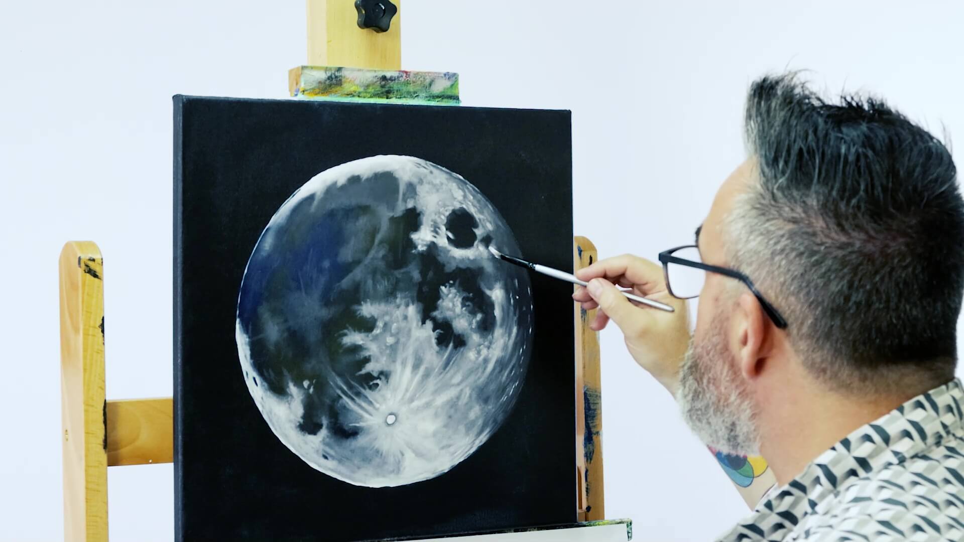 Hand painting a realistic moon artwork with Titanium white on a brush.