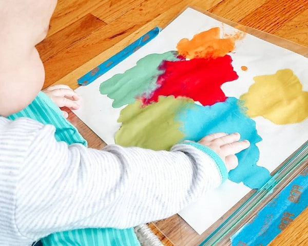 Child painting using a ziploc bag and paper.