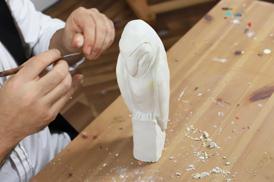 Hand creating an owl sculpture.