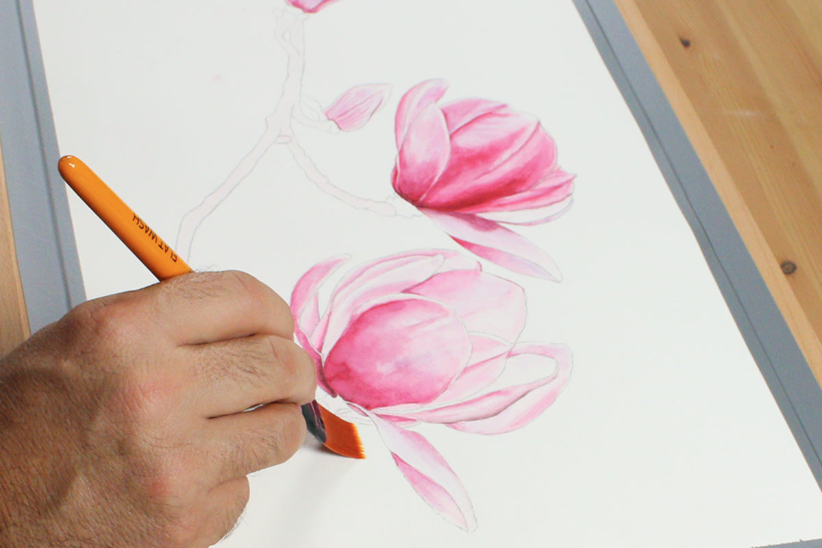 Hand painting pink watercolour flowers on white watercolour paper.