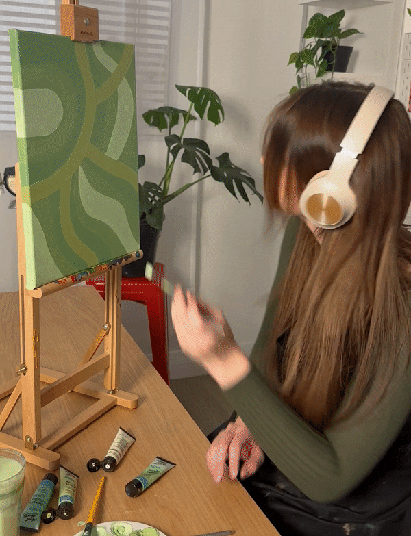 7. Green abstract painting on a desktop easel with plaints in the background