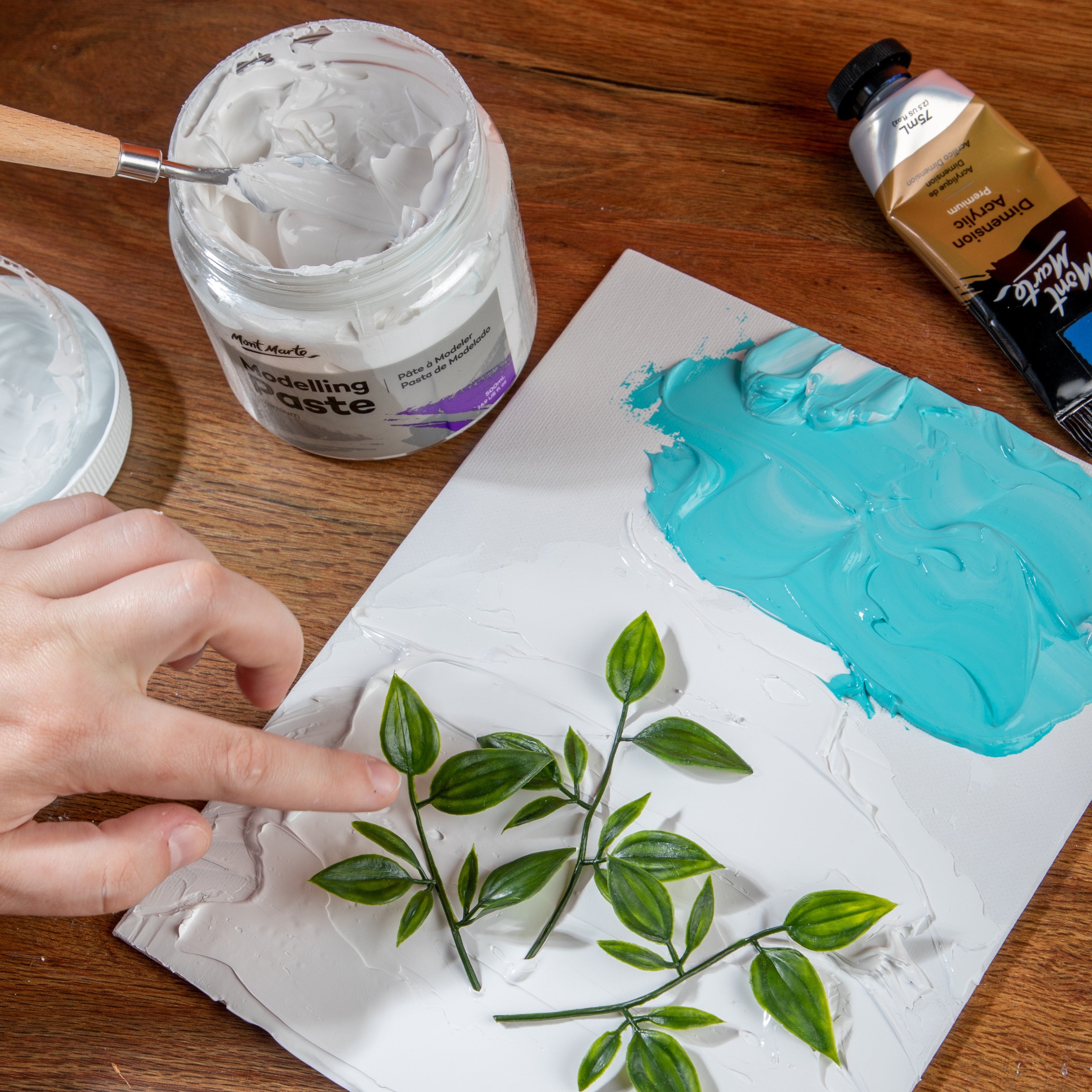 7. Modelling paste mixed with paint and being used to stick leaves to a canvas