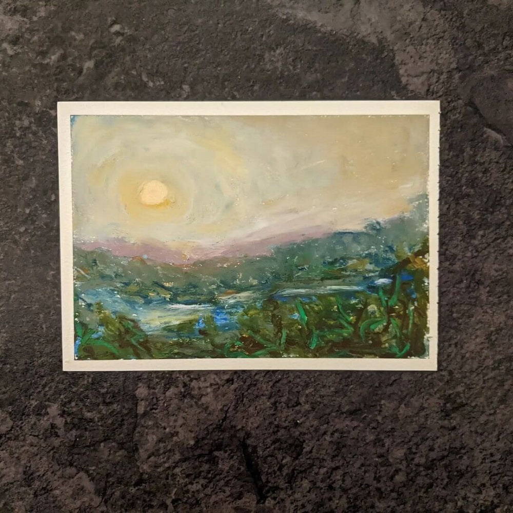 Small artwork of a sunset drawn in oil pastel on a dark surface.