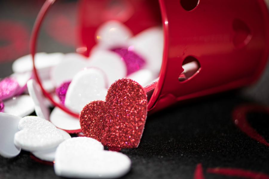 A red bucket with white and pink love hearts falling out of it. 