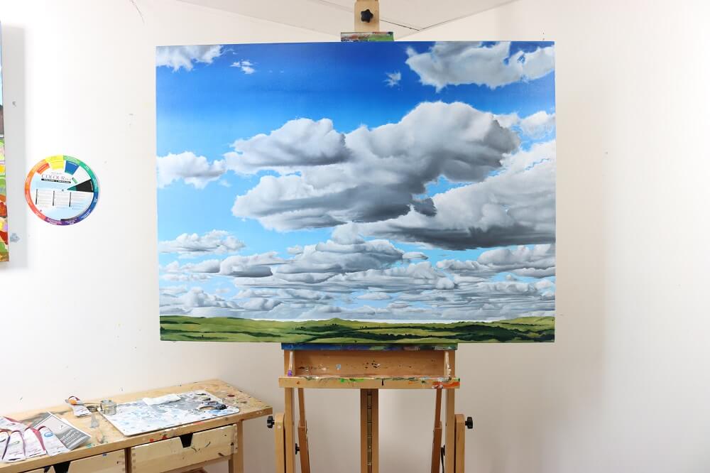 Cloud oil painting resting on an easel with a colour wheel behind it. 