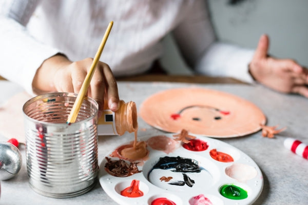 A child painting with a white paper plate.