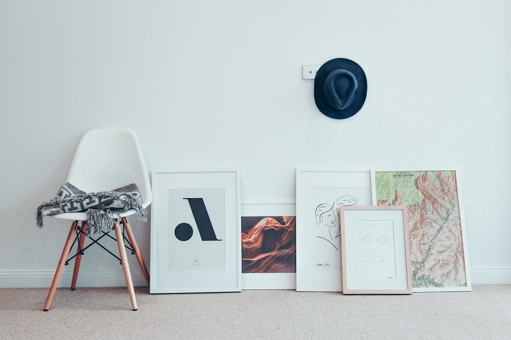 Five different frames of various artworks resting on the floor. 