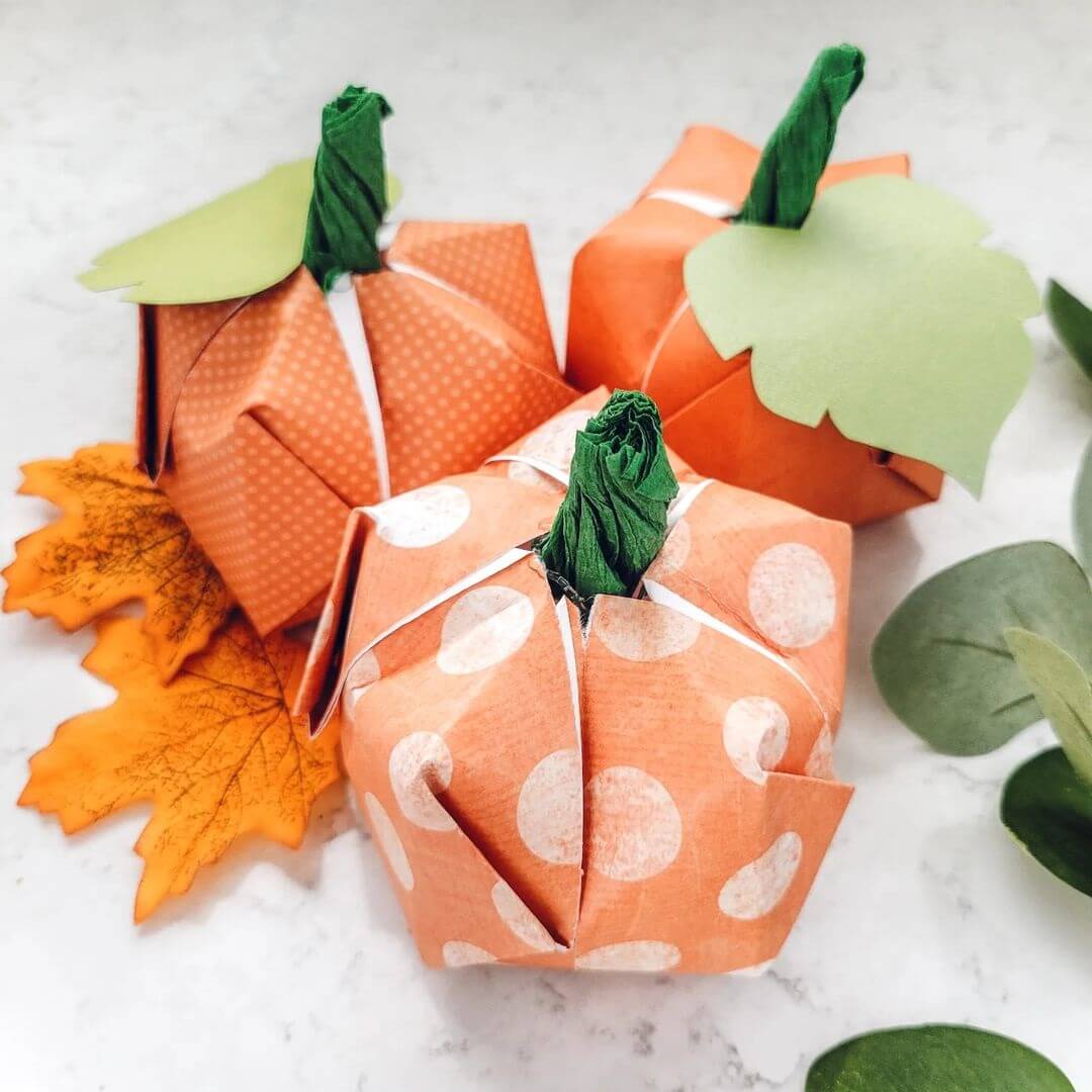 Three origami pumpkins made using various orange patterned papers.