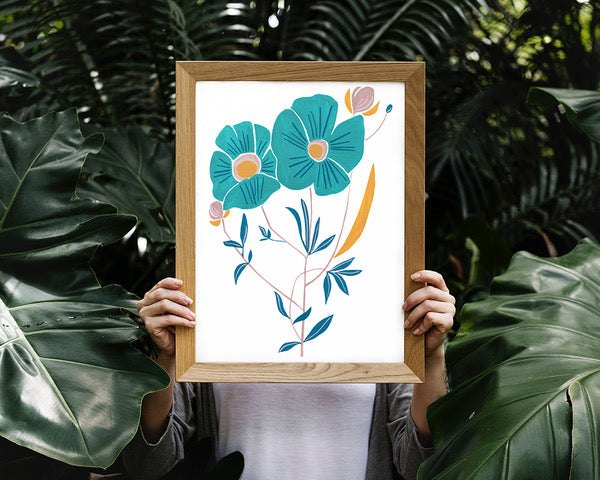 Hand holding a framed gouache artwork of flowers.