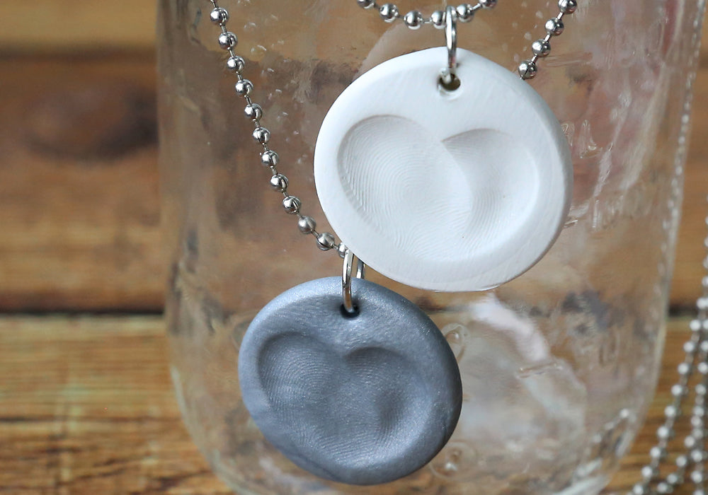 Two grey and white fingerprint necklaces.