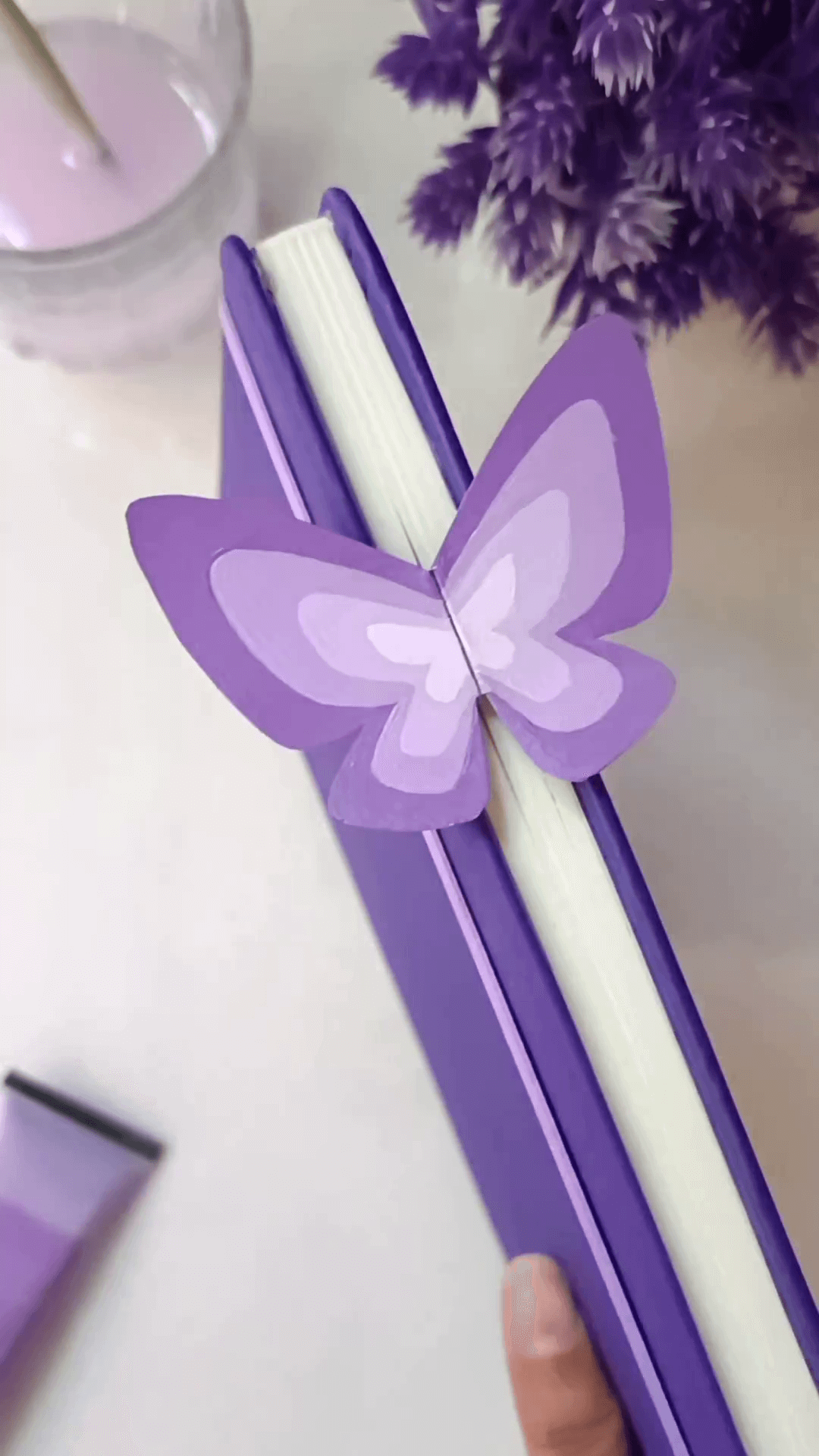 9. A purple notebook with a purple ombre butterfly book mark inside.