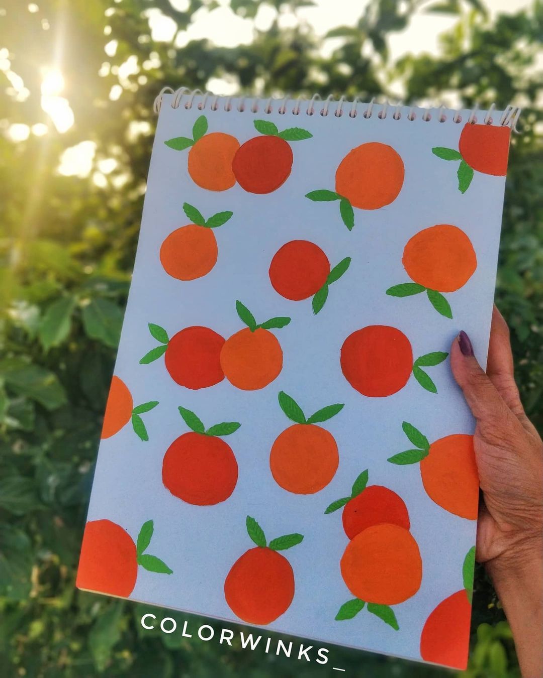 9. Bright orange pattern on white sketch paper held against a leafy background