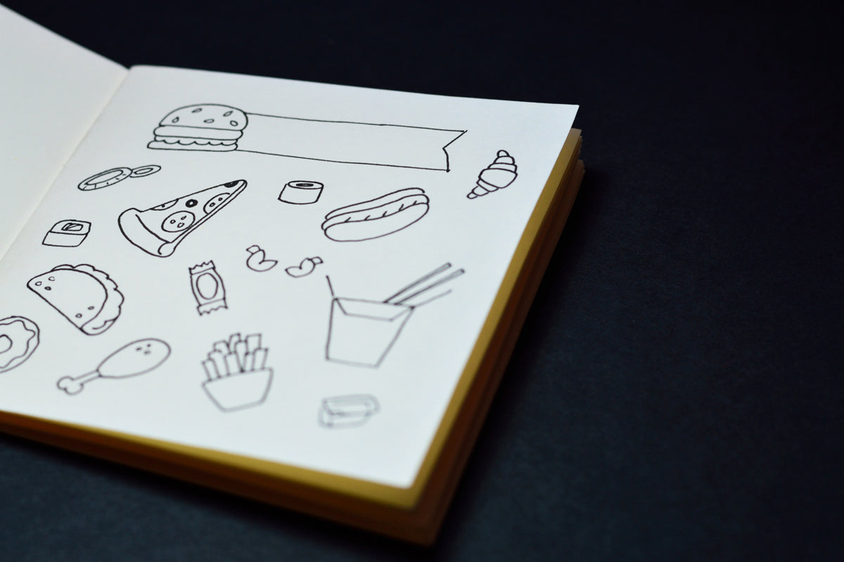 Various foods, drawn in a sketchbook on a black table.