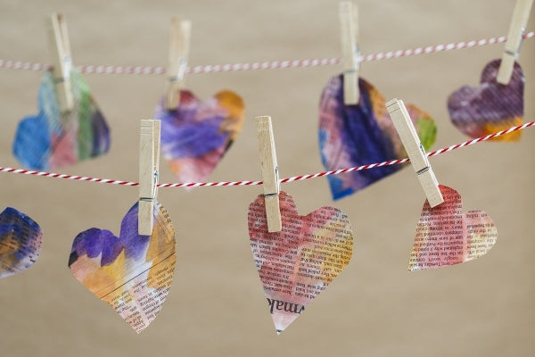 Several newspaper hearts hanging on a clothesline.