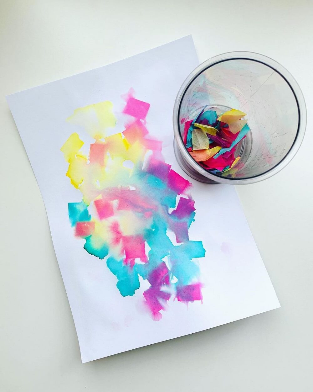 Pieces of crepe paper in a glass next to a pastel marble paper.