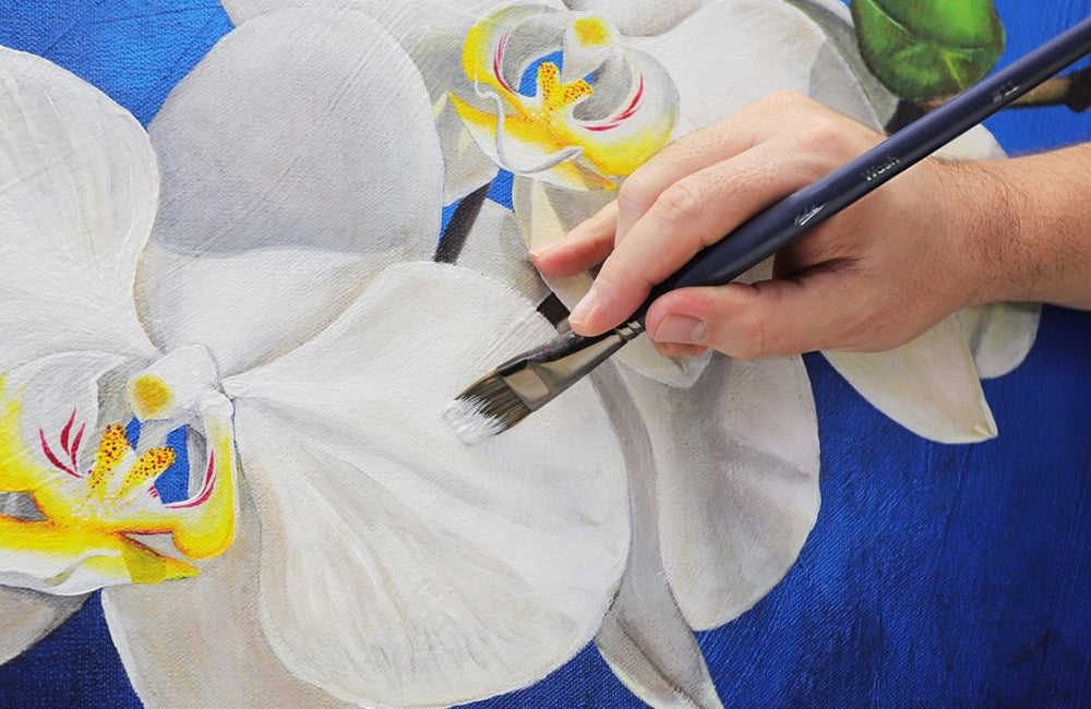 White paint being applied to a painting of an orchid