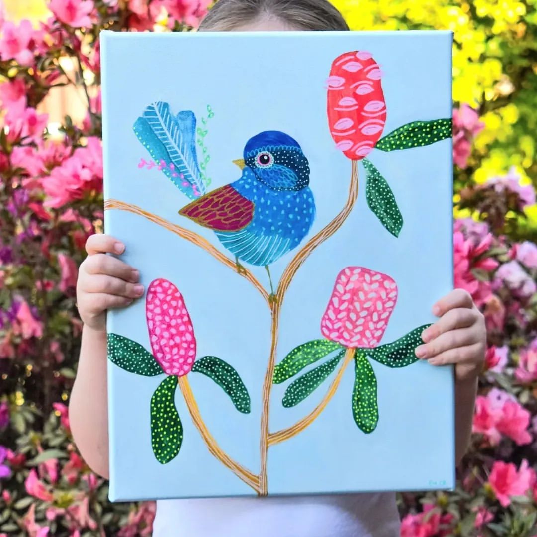 Child holding painting of a blue bird sitting on a native Australian plant