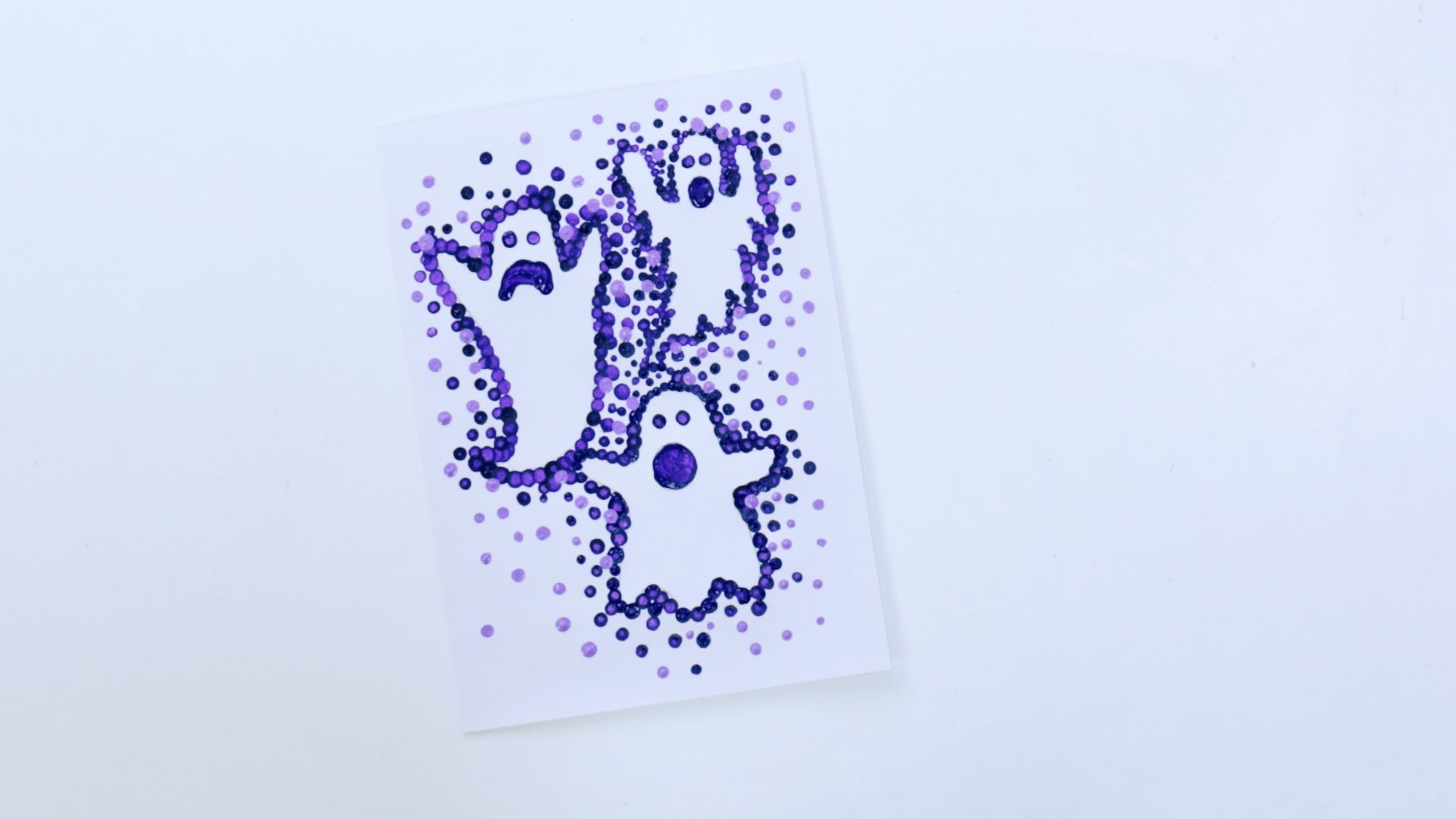 Three ghosts painted on cardboard with painted purple dots.
