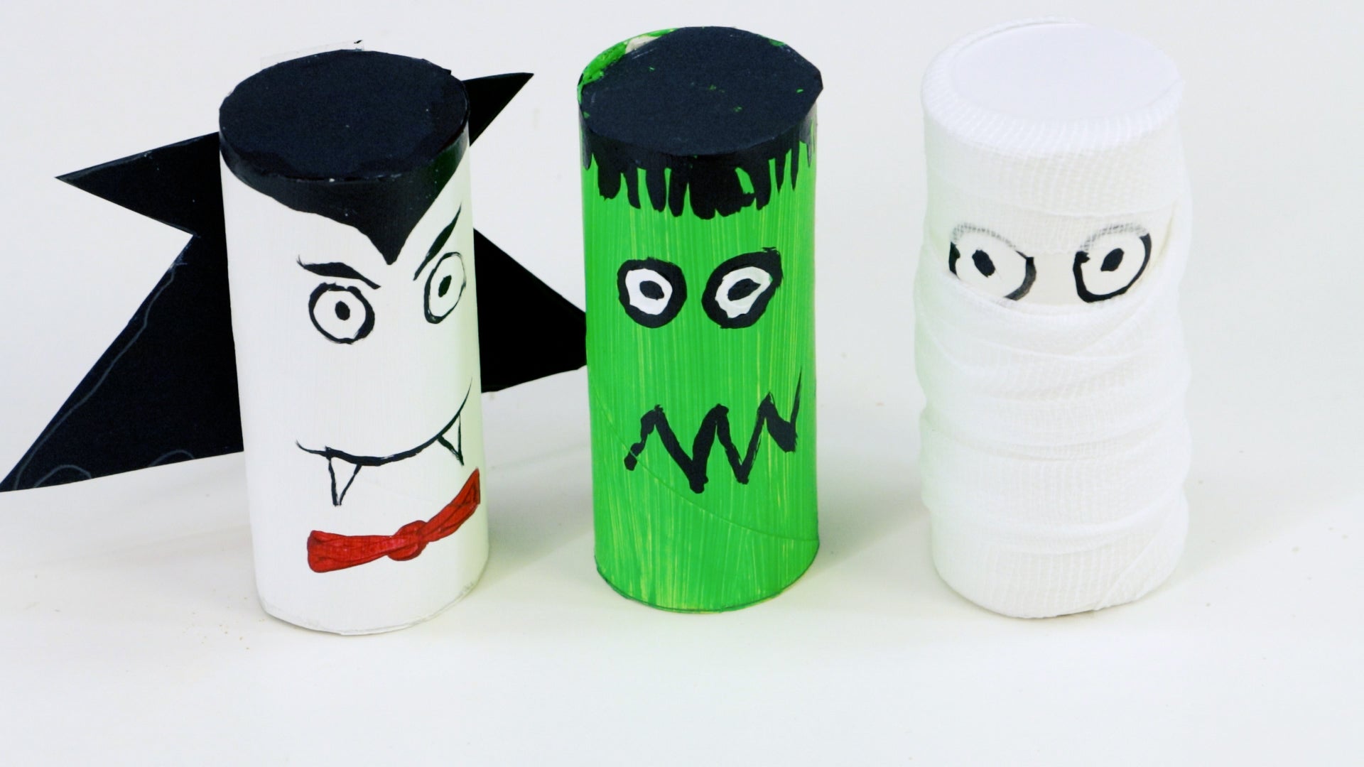 Three toilet paper rolls painted to look like Frankenstein, a mummy and Dracula.