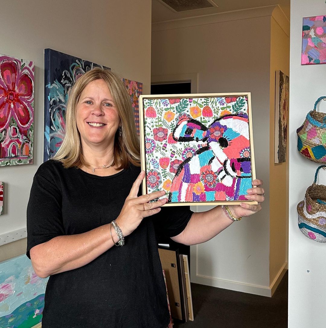 Kerrie holding a colourful, abstract turtle framed painting