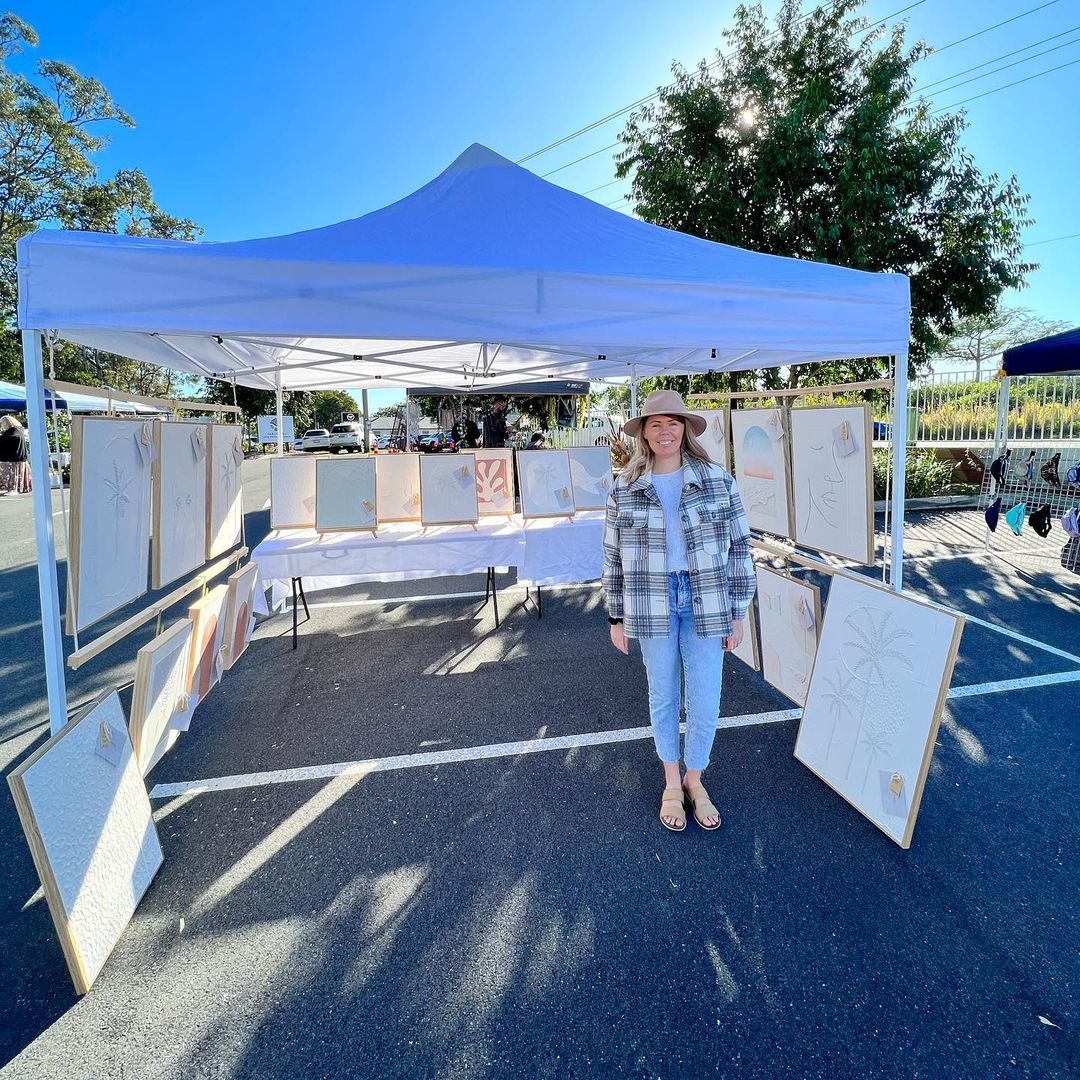 Kylie standing in front of her artwork market stall