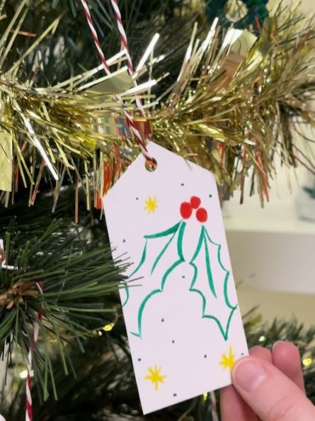 Holly gift tag hung onto an Xmas tree