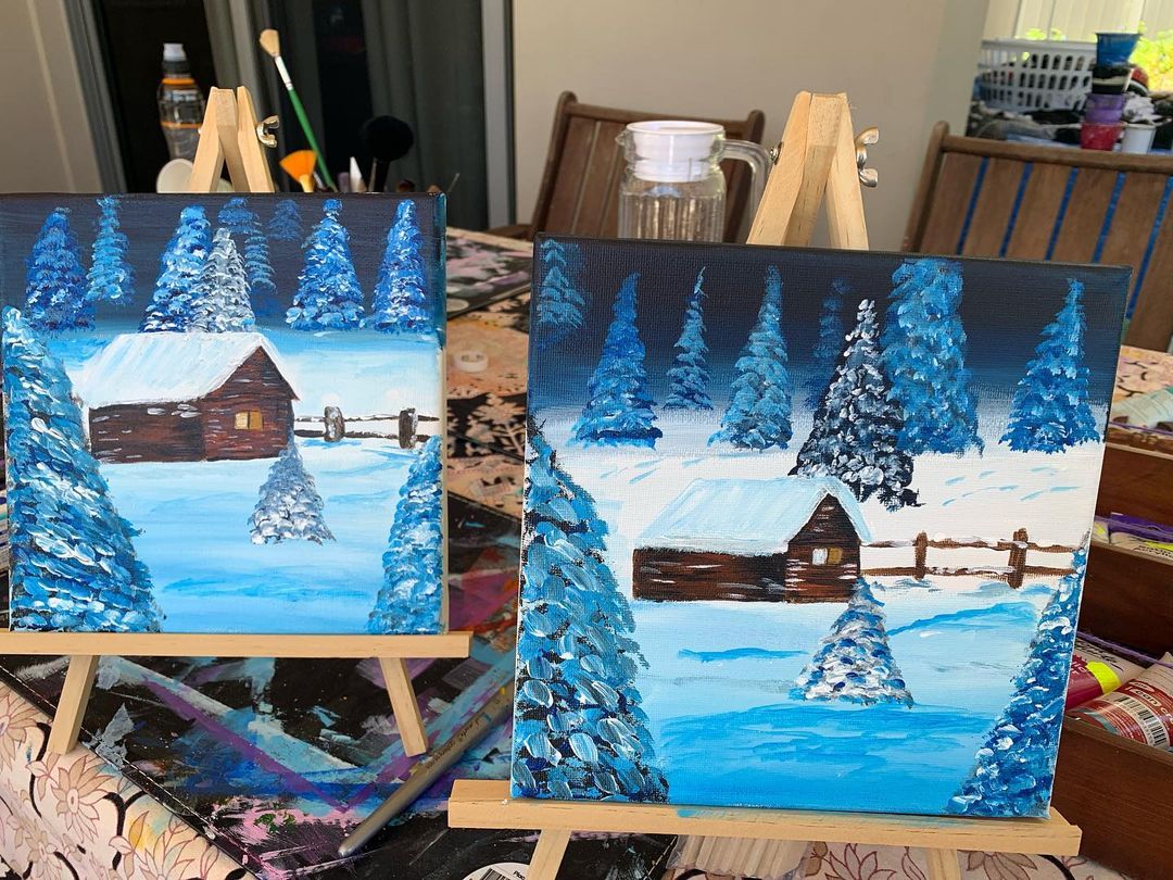 Student paintings of a winter cabin covered in snow