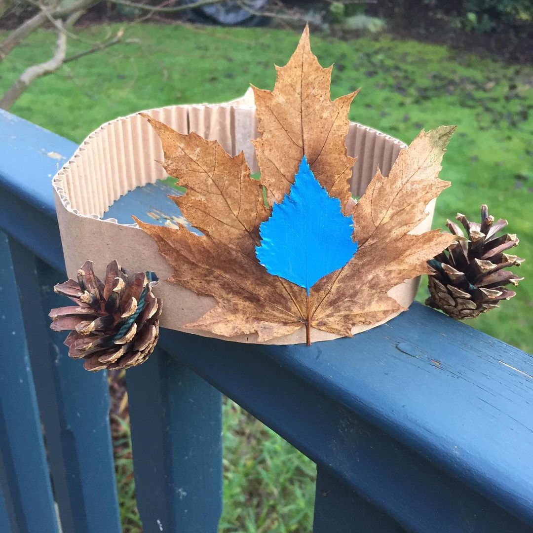 Cardboard crown with pine cones on the side and a large leaf glued to the front.