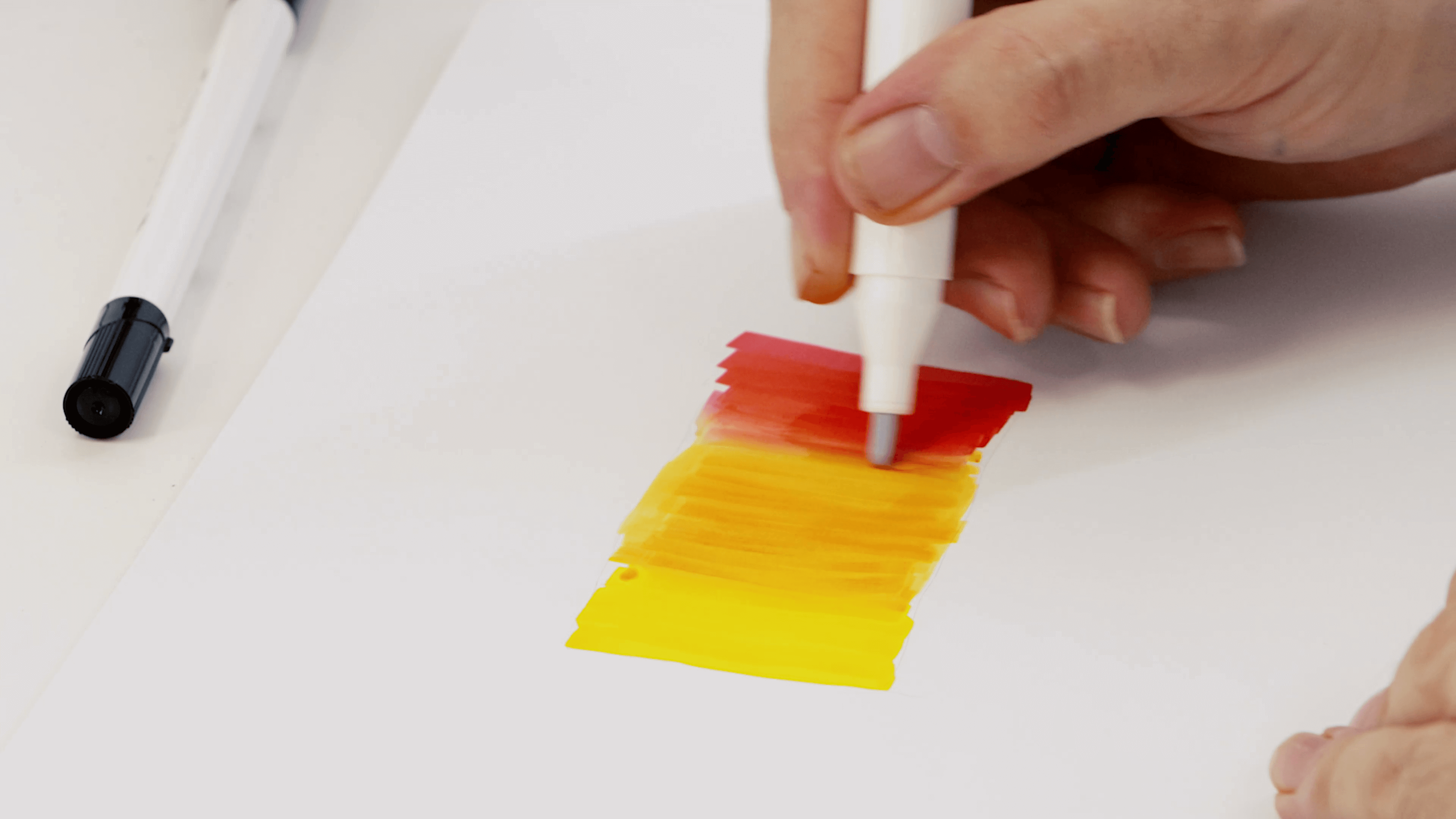 Hand blending an alcohol marker to create a red, orange and yellow gradient.