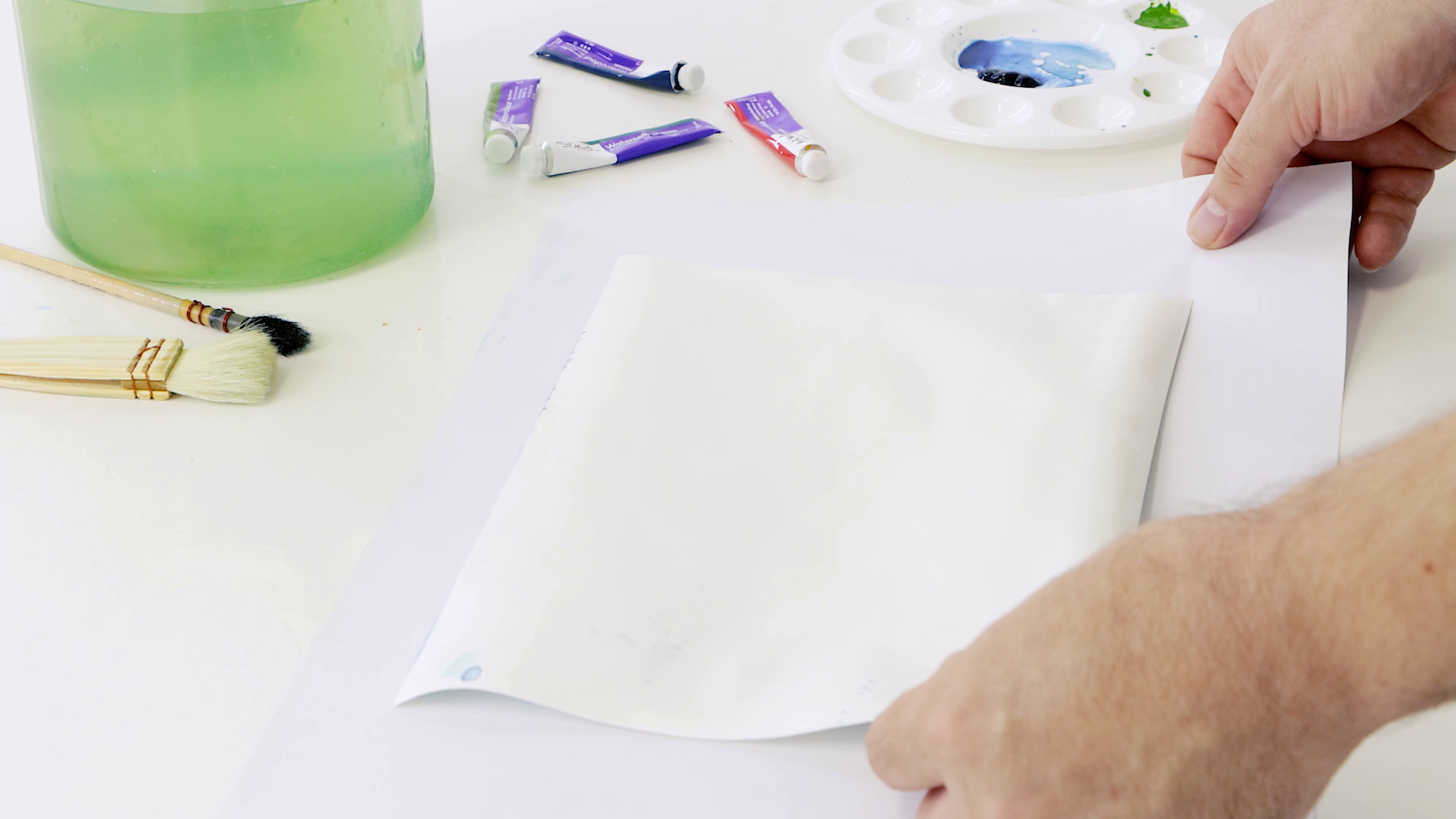 Hand fixing buckled watercolour paper by placing a damp piece of paper over the top.