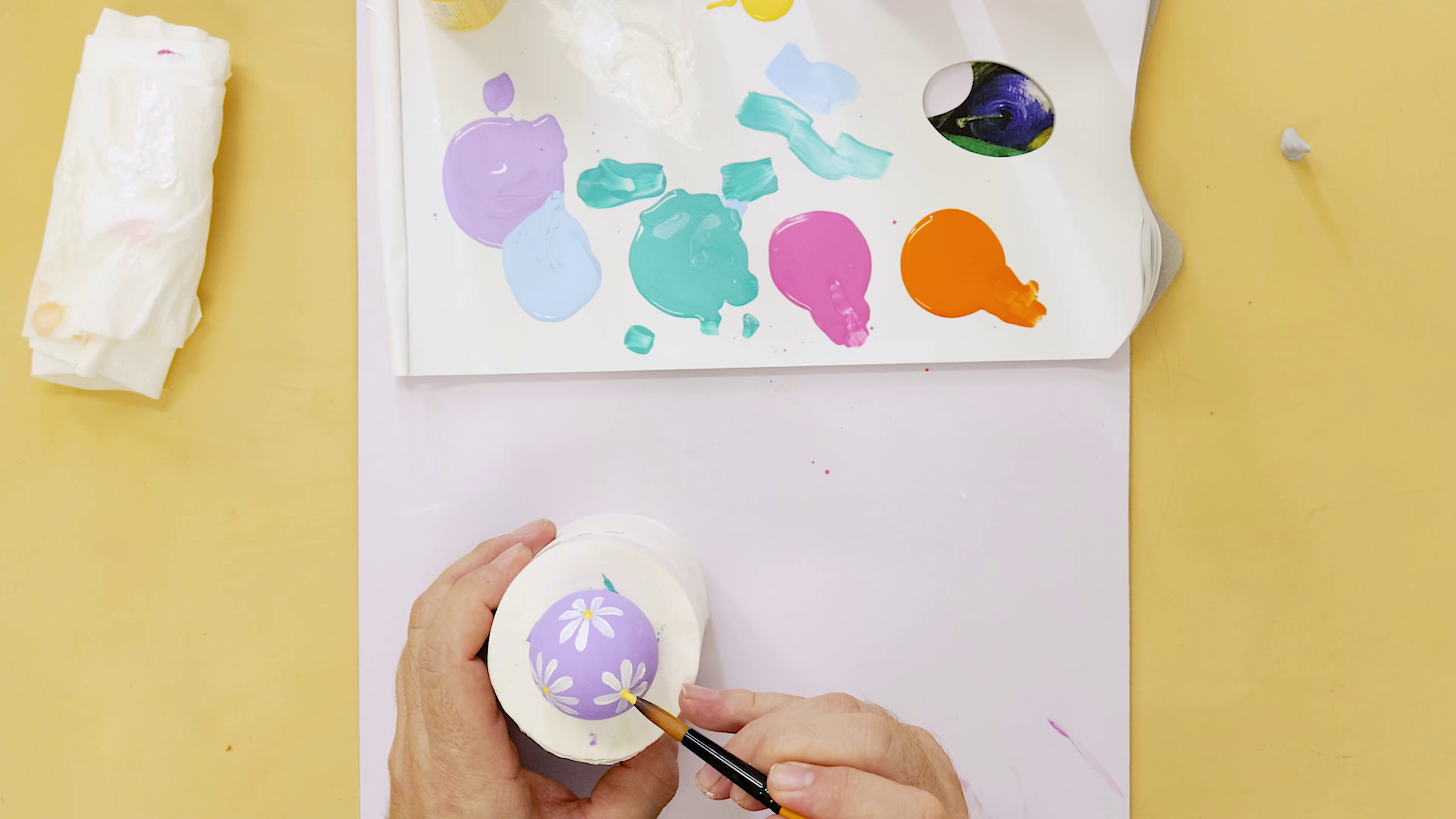 Hand painting daisies on a purple Easter egg.